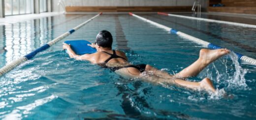 Fotografía de nadadora entrenando la patada con tabla amarilla en piscina